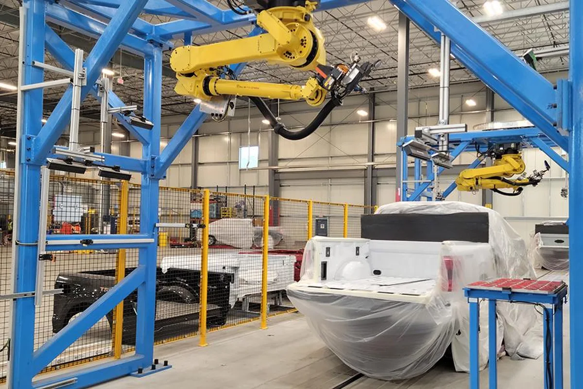 Robotic arms positioned over a masked truck bed on the GFX Solutions production line