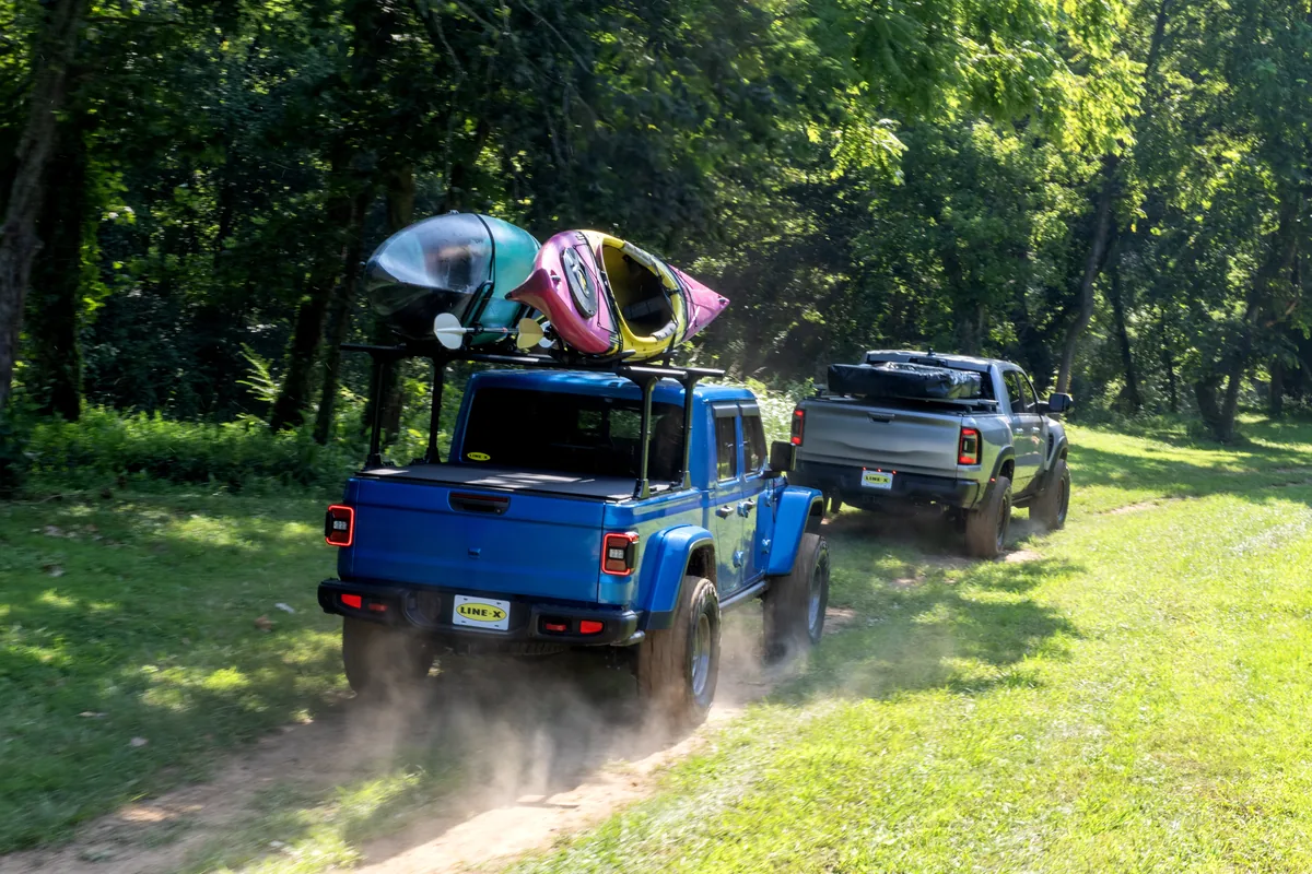 Two LINE-X-equipped trucks driving along a wooded trail