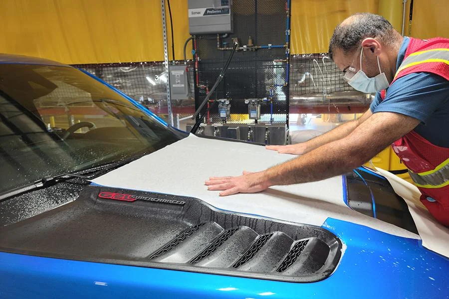 Technician applying a protective coating to a vehicle hood
